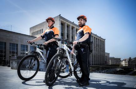 Een vrouwelijke agent en een mannelijke agent met hun fiets in de hand