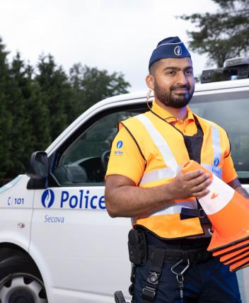 Politie-inspecteur met kegel in de hand staat aan combi